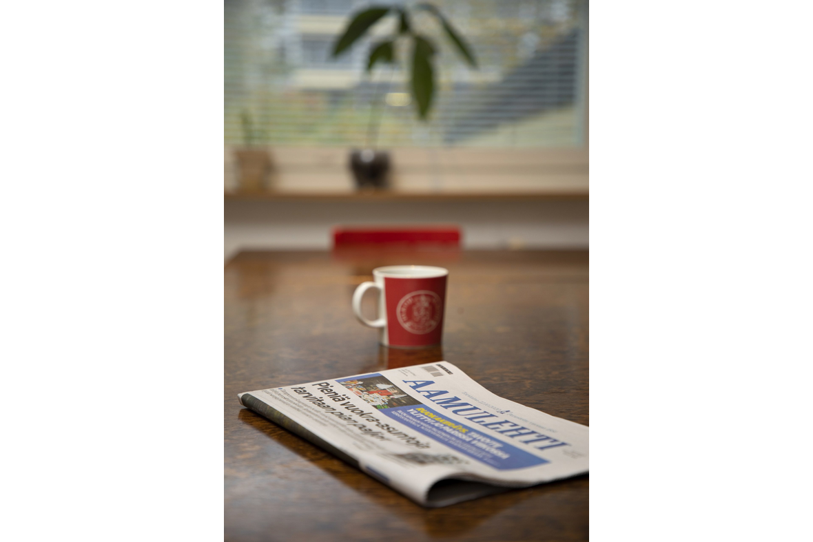 Kahvikuppi ja sanomalehti pöydällä.