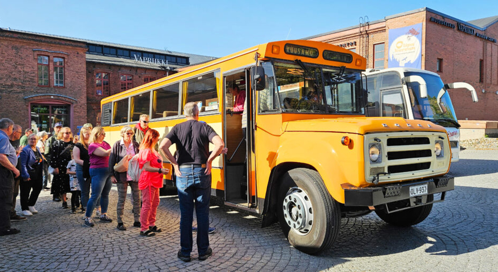 Ihmiset jonottavat postibussille Vapriikin pihalla.