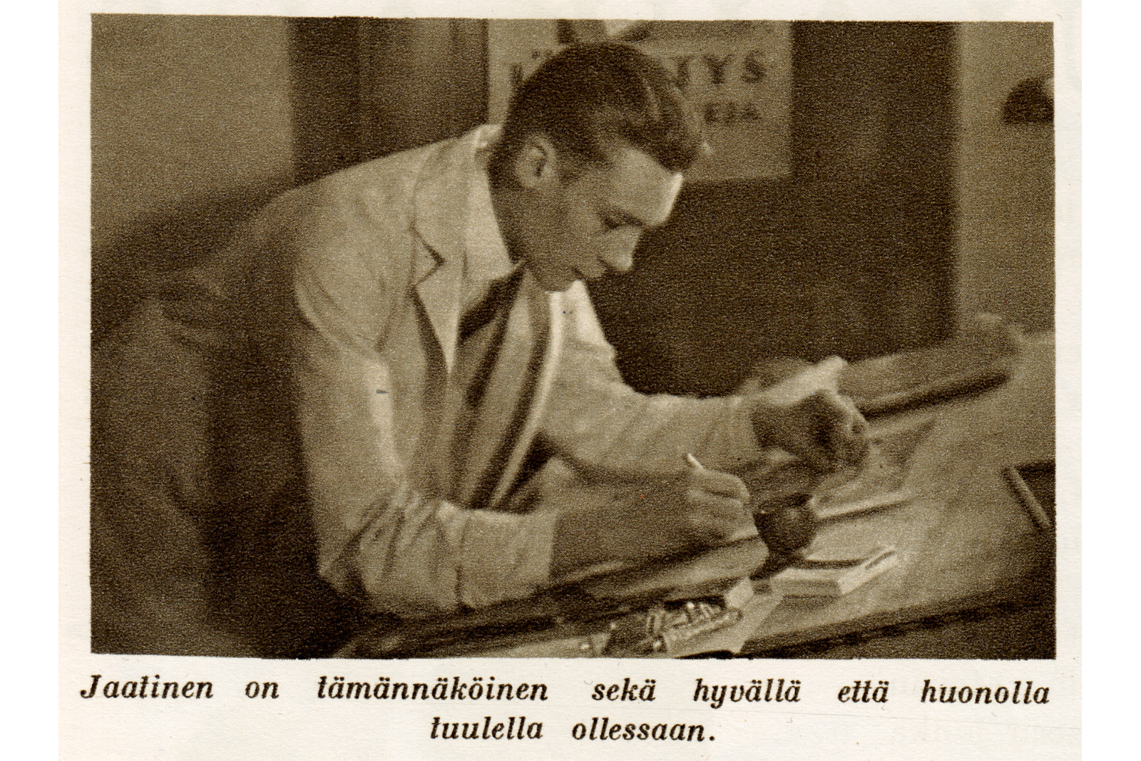 Mustavalkoinen kuva tummahiuksisesta valkoiseen takkiin pukeutuneesta miehestä piirtämässä pöytätasolla.