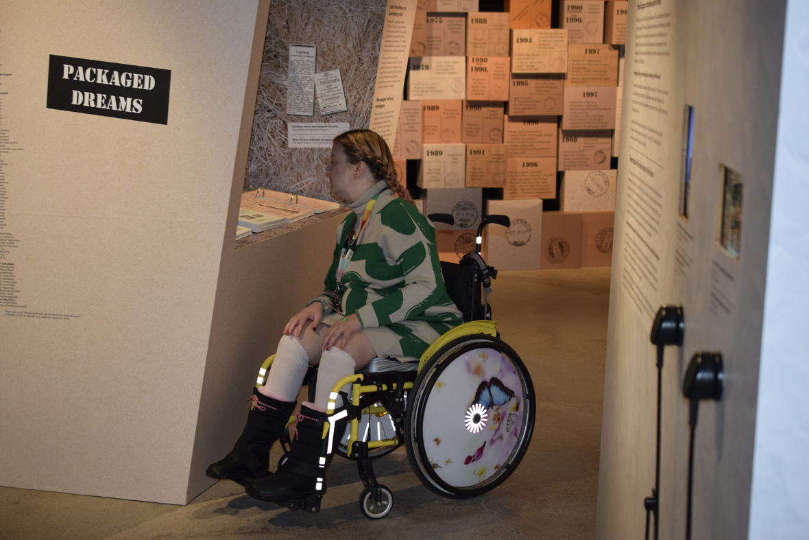 Pyörätuolissa oleva henkilö katselee näyttelyä.