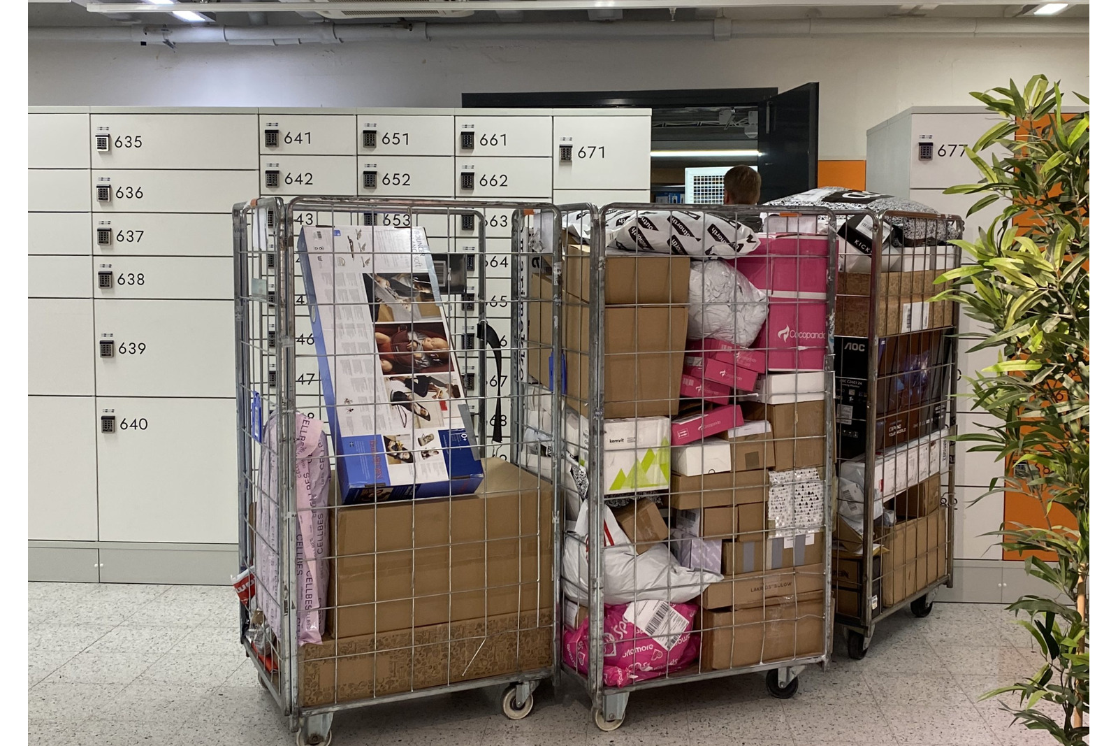Pakettiautomaatti, jonka edessä paketteja täynnä olevia kärryjä.