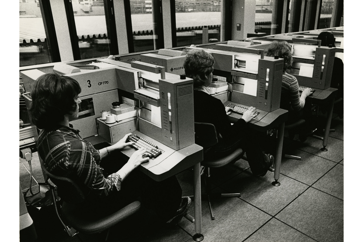 Naiset jonossa koneiden takana näppäilemässä painikkeita kuin näppäimistössä.