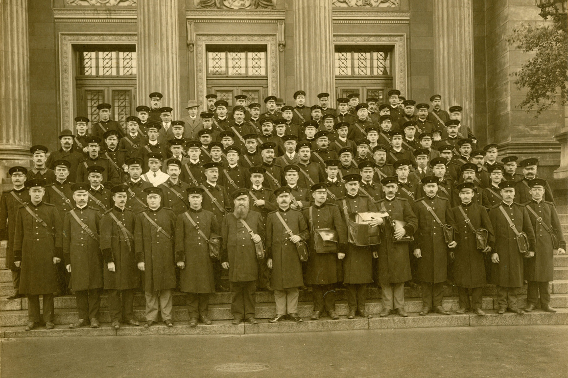 Ryhmäkuva noin seitsemästäkymmenestä postinjakajasta seisomassa Helsingin Postitalon rappusilla 1910-luvulla.
