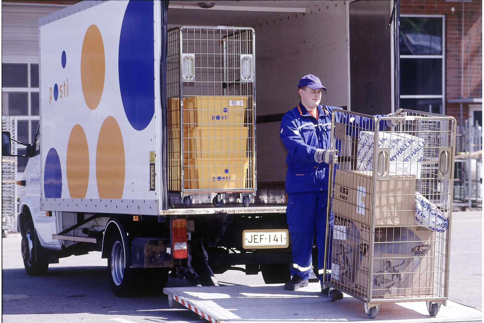 postin työntekijä purkaa postipaketteja kuorma-autosta.