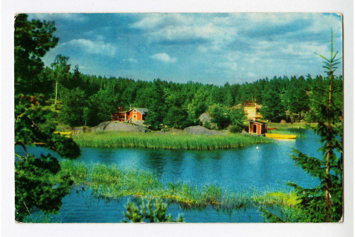 Vaakatasoinen postikortti, jossa on valokuva järvimaisemasta punaisella mökillä.