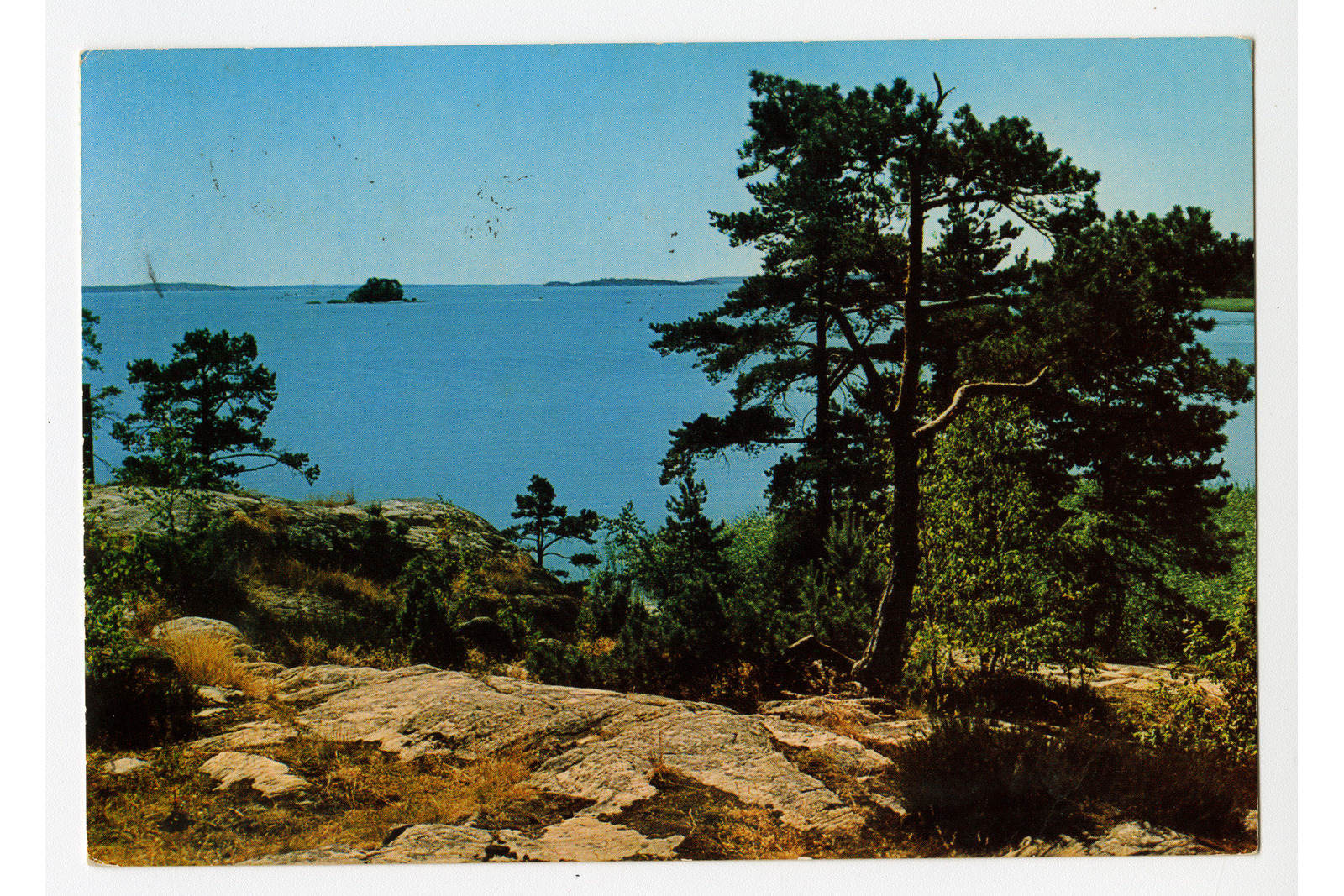 Vaakatasoinen postikortti, jossa on kuva kallioiselta kohtaa koti vesialuetta.