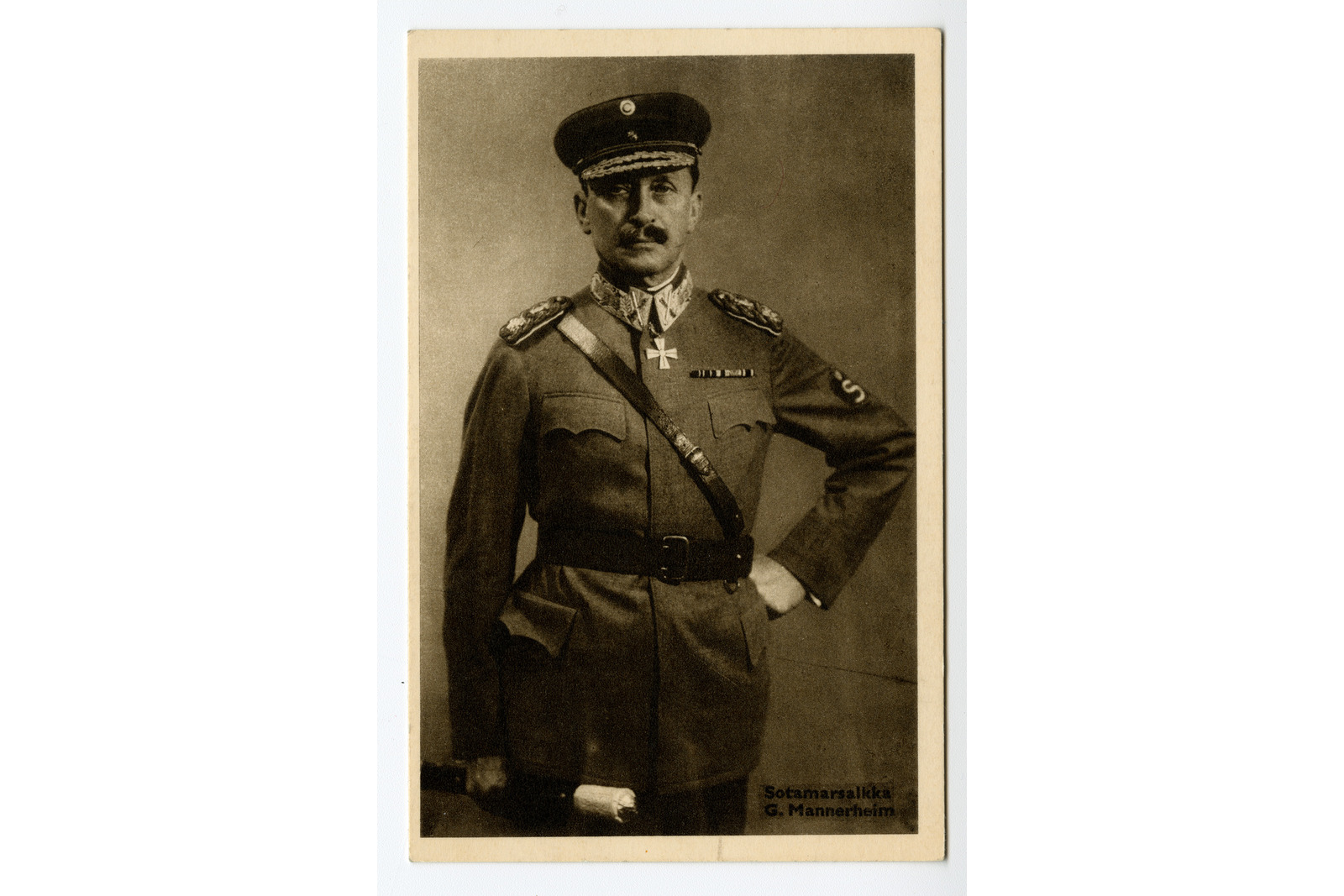 Pystymallinen postikortti, jossa on mustavalkoinen kuva Mannerheimista sotilasasussaan. Alla tekstinä Sotamarsalkka C. Mannerheim.