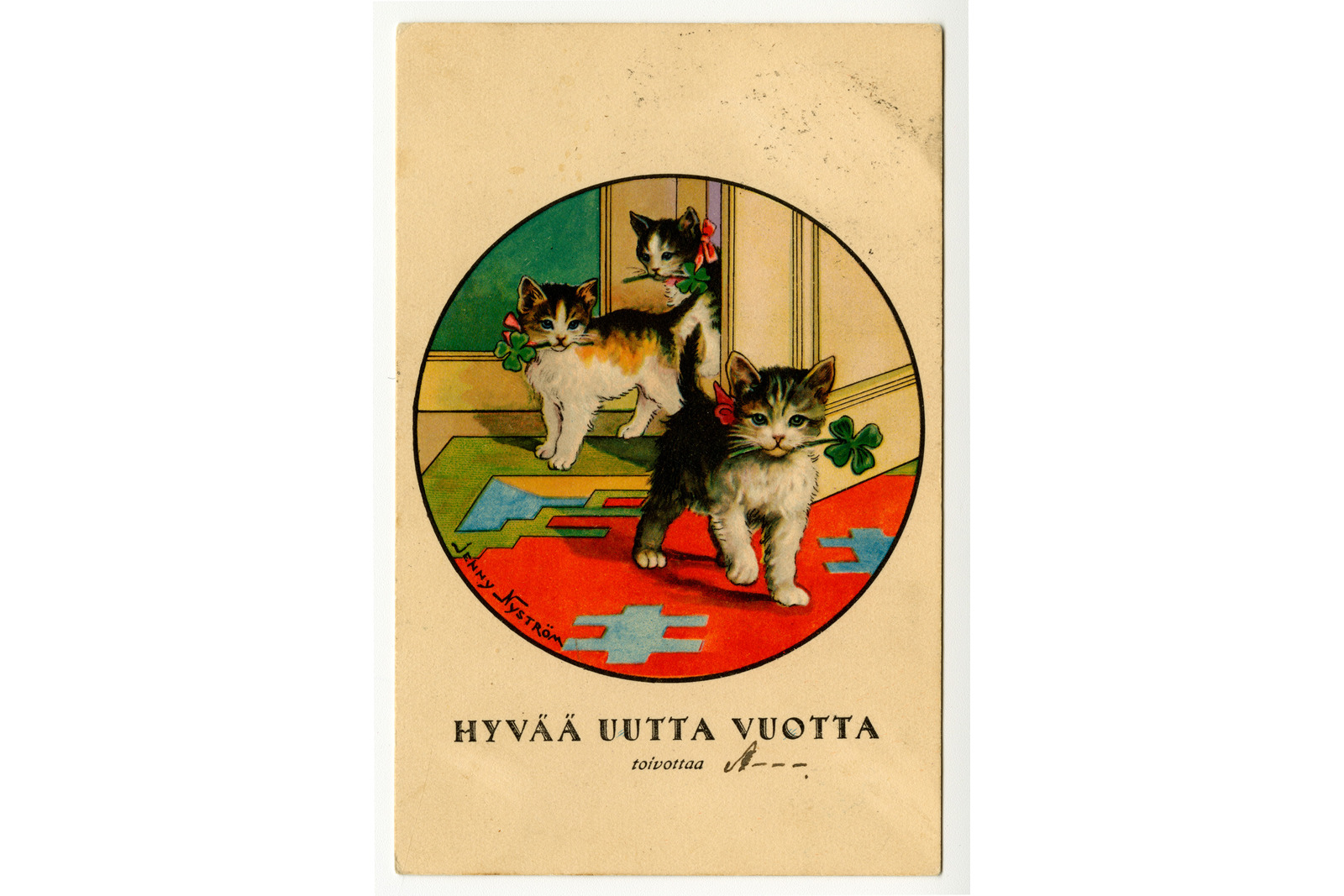 Pystytasoisessa postikortissa keskellä ympyrässä on piirroskuva kolmesta kissanpennusta tulossa sisään raollaan olevasta ovesta. Niillä on rusetit kaulassaan ja neliapila suussaan. Piirroksen sisällä on teksti jenny Nyström, alla Hyvää uutta vuotta toivottaa ja käsinkirjoitettu nimi.