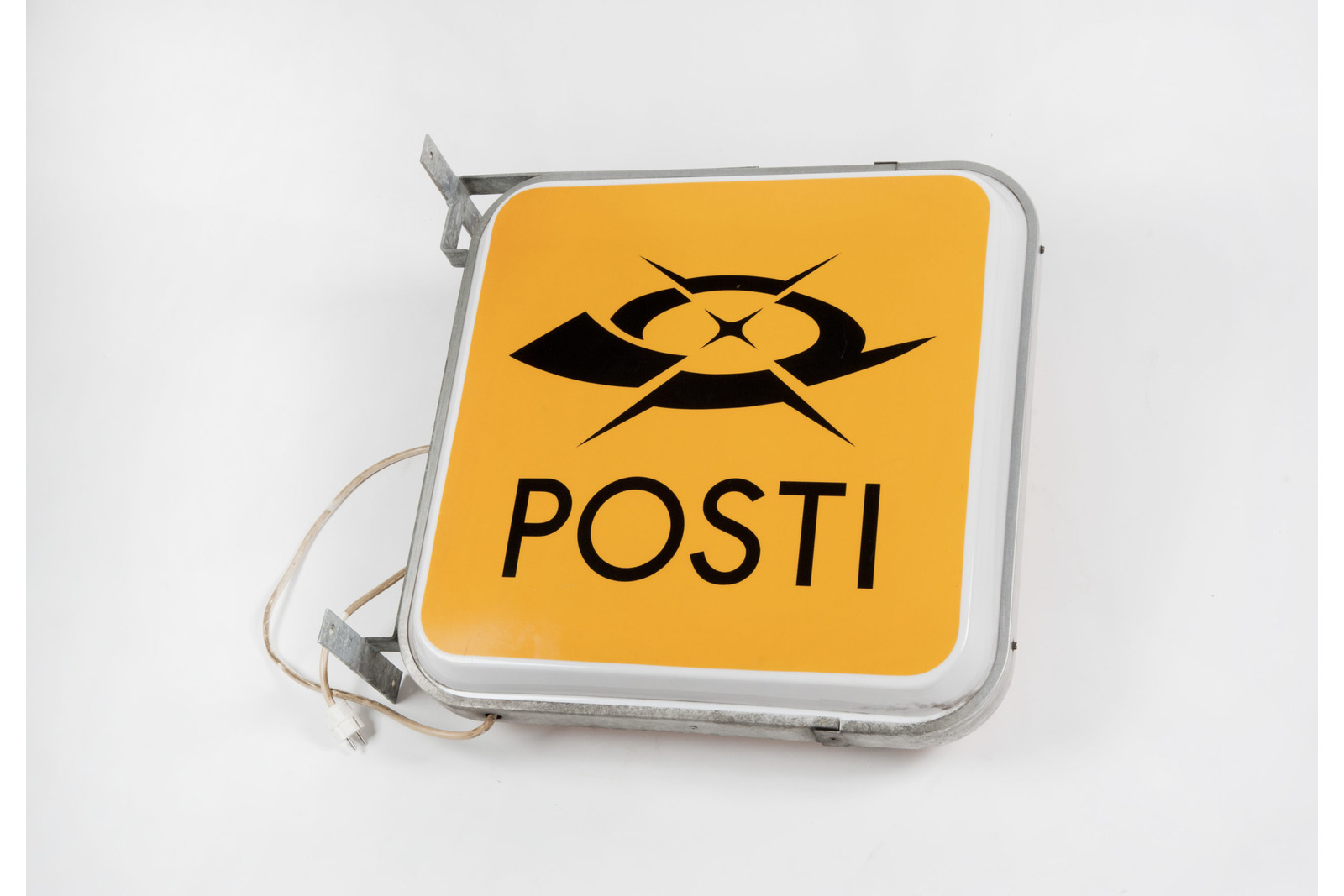 Neliönmallinen valkoisilla reunoilla oleva oranssipohjainen ja mustalla logolla varustettu Postin valomainos. Postin tyylitelty postitorvi-logo ja teksti Posti.