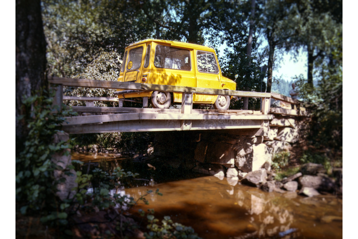 Keltainen postin auto kulkee sillalla.