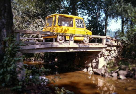 Keltainen postin auto kulkee sillalla.