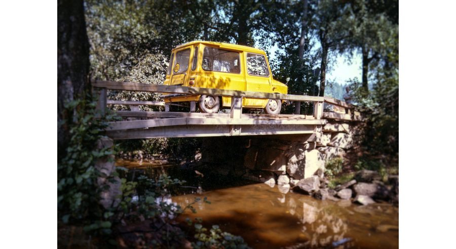 Keltainen postin auto kulkee sillalla.