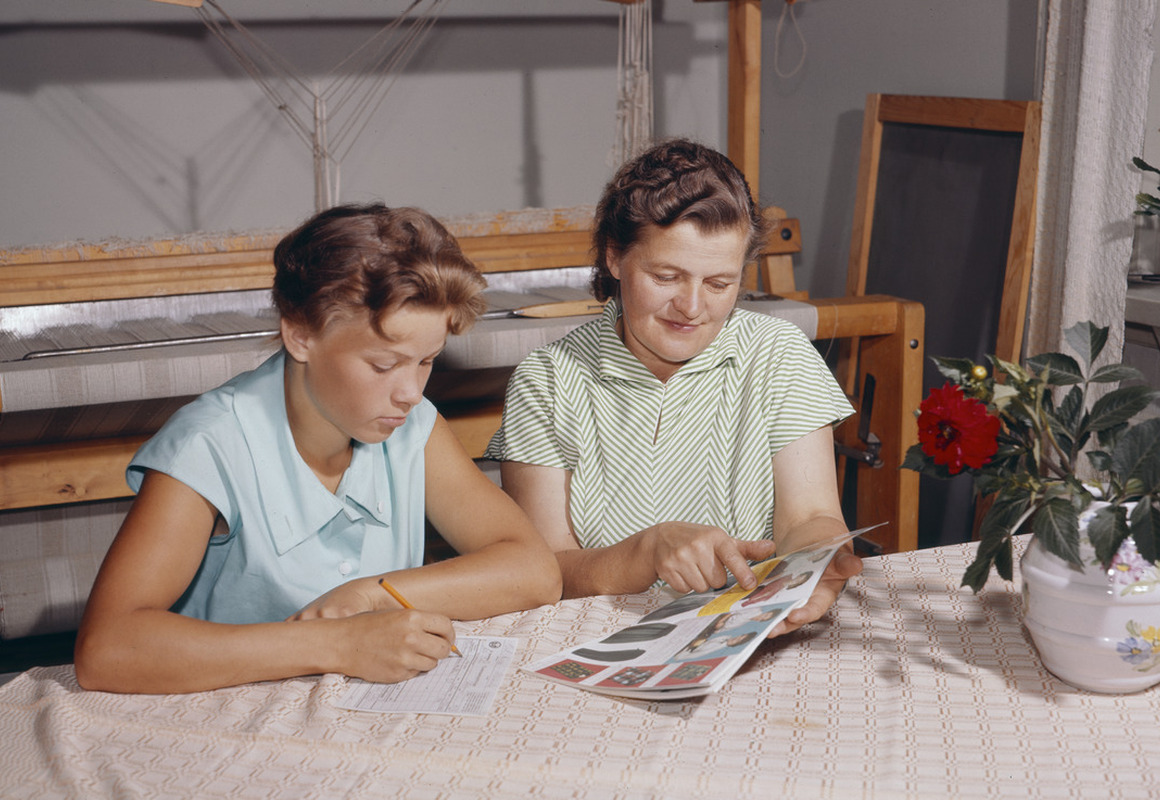 Äiti ja tytär istuvat pöydän ääressä ja täyttävät postimyyntikuvaston tilauslomaketta vuonna 1959.