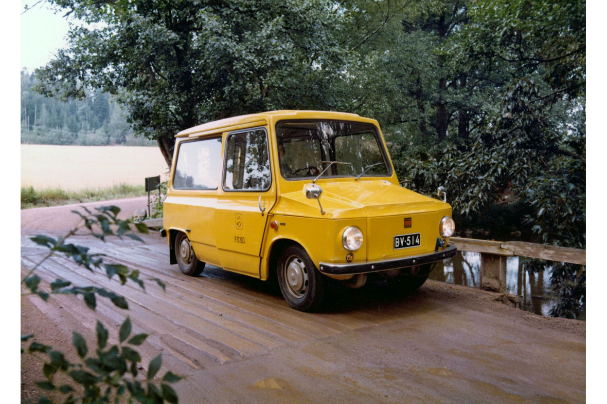 Keltainen postiauto puisella maantiesillalla.