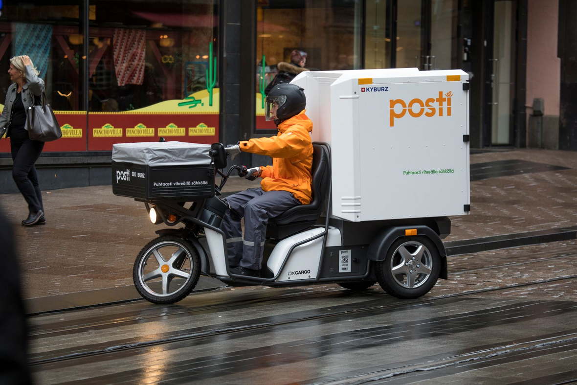 Postinjakaja ajaa kolmipyöräisellä sähköskootterilla mukulakivikadulle.