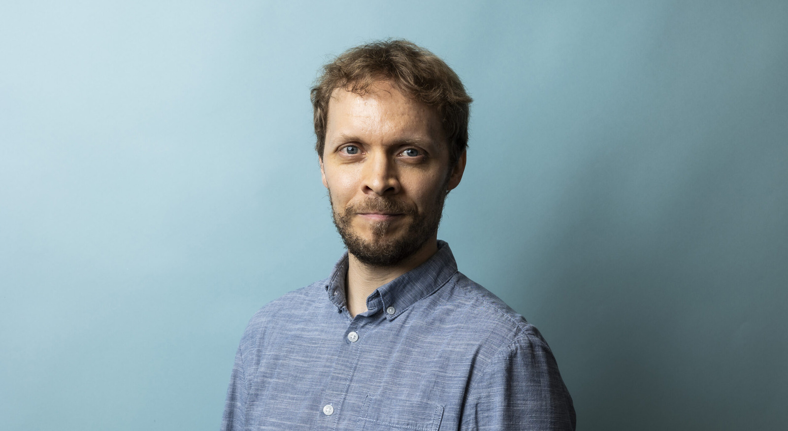 Nuorehko, vaalea mies muotokuvassa sininen kauluspaita päällään.