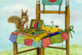 Pystymallinen piirroskortti, jossa siveltimistä ja kynistä rakennettu tuoli, jonka päällä tilkkusuojus paperia, värikyniä ja yhtä värikynää pitävä orava.
