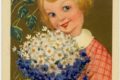Pystymallinen postikortti, jonka yläosassa ruutupunamekkoinen, vaaleahiuksinen, hymyilevä tyttö on kukkakimpun kanssa, Kukkakimpussa on päivänkakkaroita ja sinivuokkoja. Alla painettuna kaunolla teksti Äidille!.