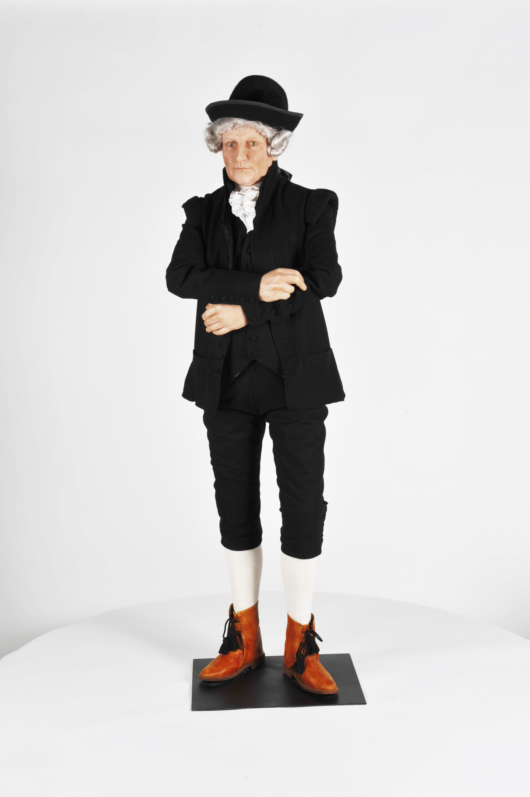 Mallinuken päällä 1700-luvun virkapuku, jossa on hattu, takki, valkoinen kaulusröyhelö, housut ja polvisukat sekä kengät.