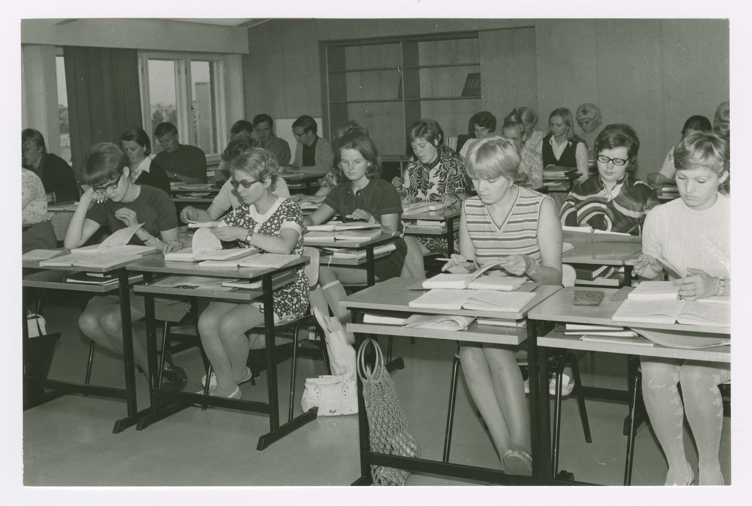 Mustavalkoisessa kuvassa ihmisiä luokassa opiskelemassa.