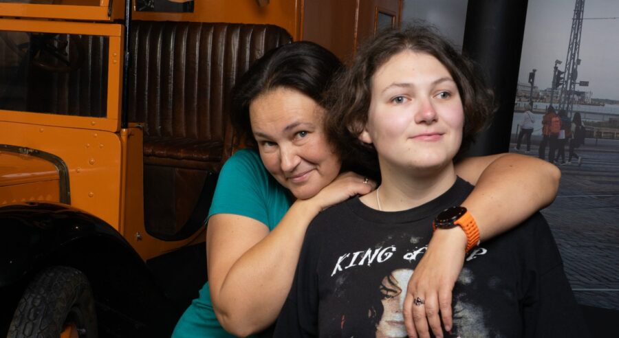 Kaksi ihmistä poseeraa vierekkäin vanhan auton edessä.