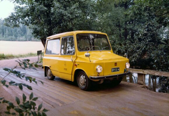 Keltainen postiauto puisella maantiesillalla.