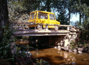 Keltainen postin auto kulkee sillalla.