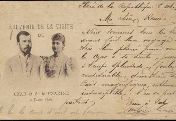 Vaakatasoinen postikortti, jossa painettuna tekstinä mustavalkoisen kuvan ylä- ja alapuolella ranskaksi Souvenir De La Visite du Czar et de la Czarine á Paris 1896 eli Tsaarin ja tsaarinnan vierailun muistoksi Pariisissa 1896. Kuvassa Venäjän keisari Nikolai II ja hänen puolisonsa. Oikealla puolella käsinkirjoitettua tekstiä ranskaksi. Kuva: Olavi Hankimon kokoelma.