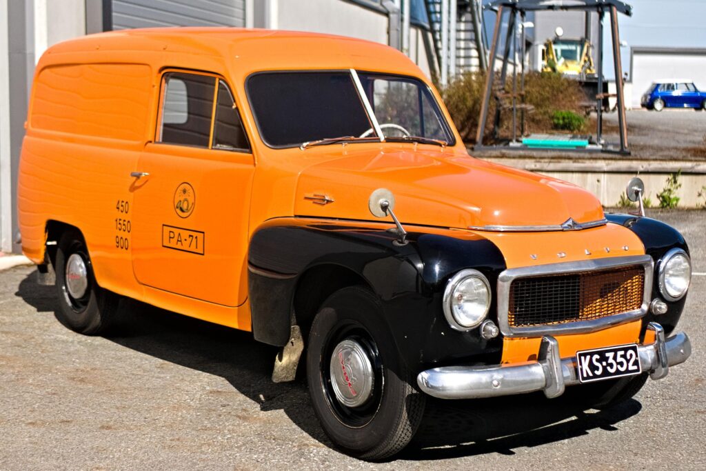 Oranssi vanha auto pihalla.