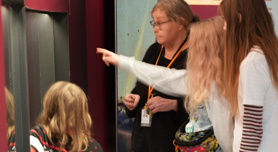 lapsia katsomassa näyttelyä oppaan kanssa.