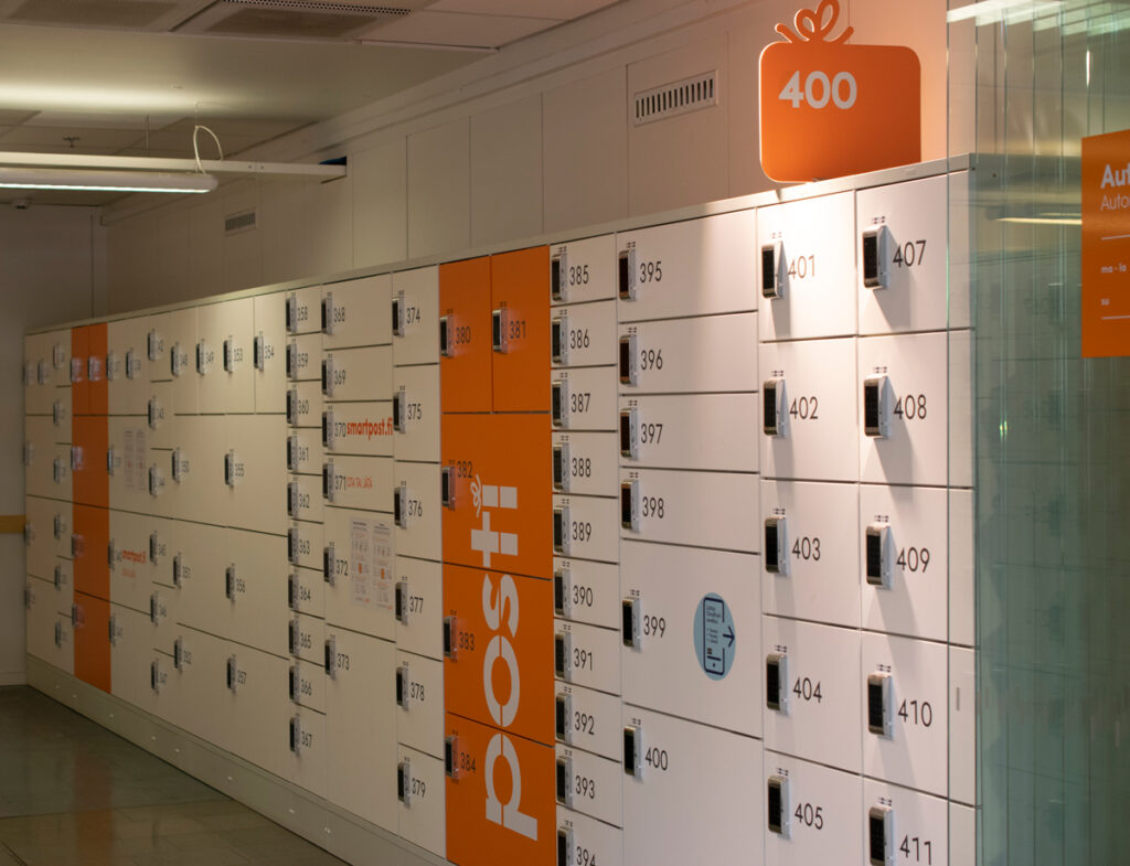 Postin valko-oranssi pakettiautomaatti kuvattuna sivulta.