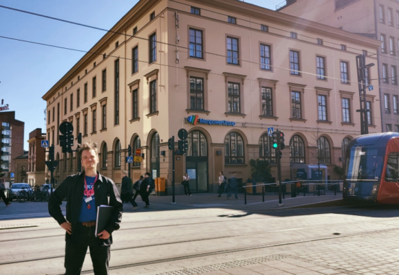 Nuori mies seisoo kadulla takanaan vanha rakennus.