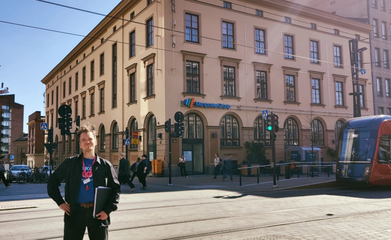 Nuori mies seisoo kadulla takanaan vanha rakennus.