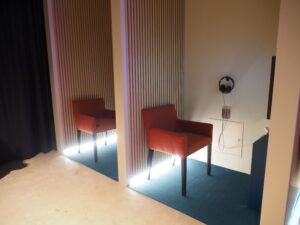 Kaksi soppea, joissa on selkänojallinen tuoli. Toisessa näkyy kuulokkeet.